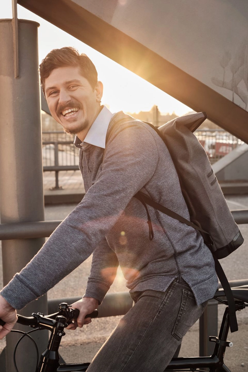 Ein lachender JobRadler fährt im Sonnenuntergang über eine Brücke