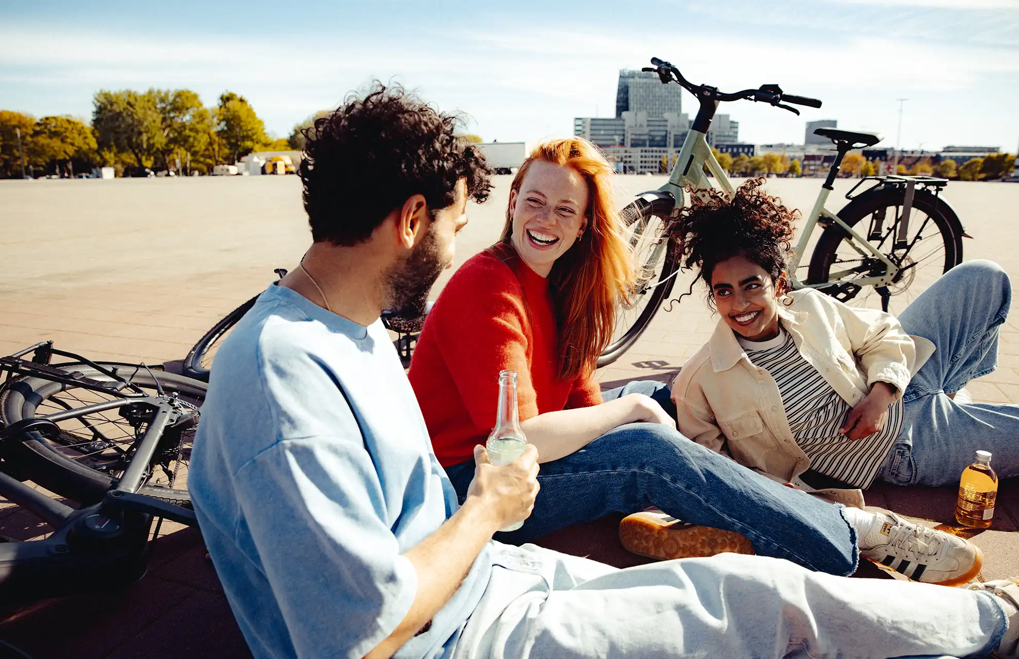 Gruppe junger Menschen mit ihren Fahrrädern auf einem urbanen Platz trinken Limo